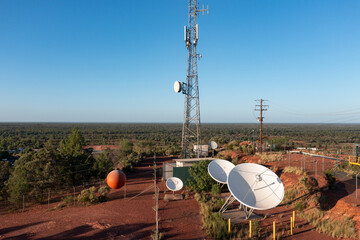 Aerial view of satellite dishes at the base of a communications tower in a barren outback setting