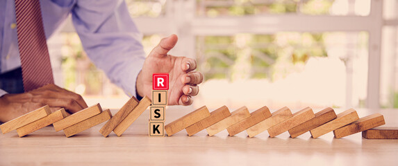 Close-up hand prevent wooden block not falling domino concepts of financial risk management and...
