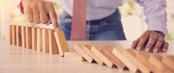 Close-up hand prevent wooden block not falling domino concepts of financial risk management and...