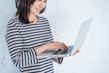 Naklejka premium 明るいリビングでノートパソコン作業でする30代女性の手元