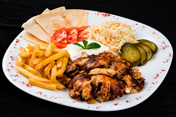 Dinner fried chicken with french fries, coleslaw, tomatoes, pickles, sour cream and pita bread.