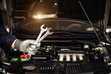 Obraz premium Car care maintenance and servicing, Close-up hand technician auto mechanic using the wrench to repairing change spare part car engine problem and car insurance service support.