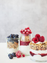 Appetizing healthy breakfast consisting of jar with yogurt and granola topped with ripe berries served on table