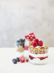 Delicious healthy breakfast made of yogurt with berries and granola served in glass jar on table