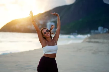 Foto op Plexiglas portrait young brazilian woman with arms raised smiling happy on Ipanema beach in Rio de Janeiro © oscargutzo