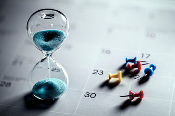 Hourglass on calendar with thumbtacks - 565359822