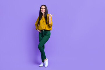 Fototapeta na wymiar Full body photo of cheerful pretty lady look indicate thumb finger empty space isolated on violet color background