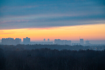 Fototapeta na wymiar early winter cold dawn over dark city park and houses on horizon