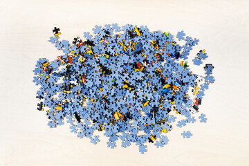 top view of pile of puzzle pieces on light brown wooden table