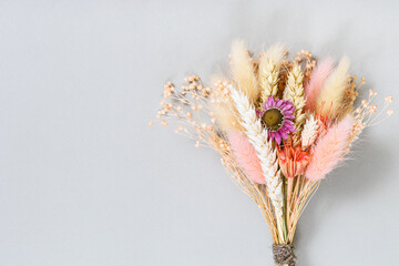 tied bouquet of dried flowers and spikelets on gray background with copyspace