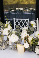 Composition with fresh white flowers and candles for wedding table. Decorations and details for celebration 