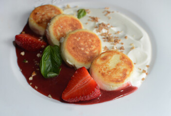 Cheesecakes with strawberry sauce on a white plate