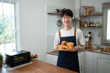 man in apron rolling out dough for homemade pastry, enjoying preparing biscuit cookies in modern light kitchen.