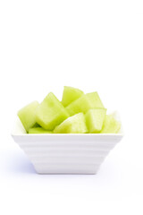 trozos de Melón Dulce Calameño (Cucumis melo) sobre recipiente de loza blanca y fondo homogéneo 