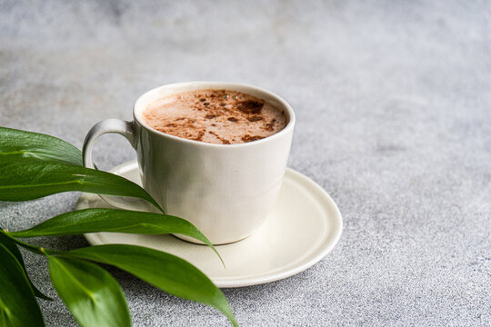 Cup of cappuccino and green leaves