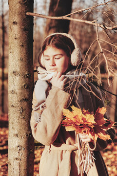 Pensive stylish teen girl model in beige coat in fall park outdoor, thoughtful sad eyes. Pretty young lady with autumn leaves leisure. Fashion youth style concept. Copy text space for advertising