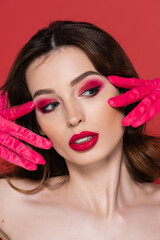 portrait of young woman with magenta color eye makeup posing in bright gloves isolated on pink.