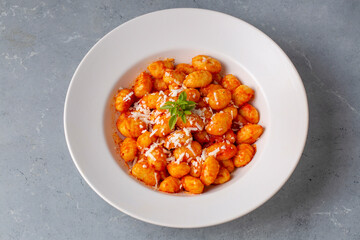 Traditional Italian food potato gnocchi with tomato sauce, parmesan cheese and fresh basil on dark table. Top view. Healthy food.
