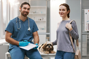 Young female owner of yorkshire terrier, her pet and veterinarian