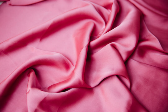 A Folded Pink Silk Fabric Lies In Folds On The Table. Drapery Texture. Synthetics Atlas