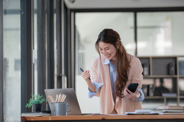 Asian women celebrate success or happy poses with a laptop.