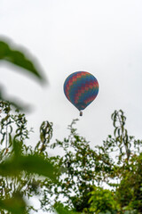 Obraz premium hot air balloon in a clear sky and between trees a balloon ride
