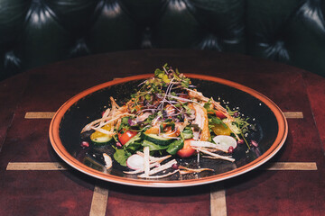 Delicious gourmet salad on a wooden table with dark background