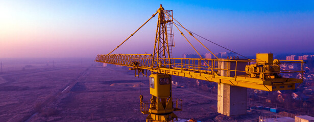 construction crane and construction site against the background of the morning or evening sky.