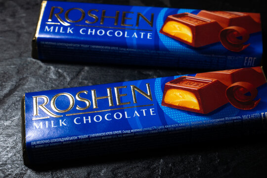 LVIV, UKRAINE - January 25, 2023 : Roshen Milk chocolate bar on black background. Ukrainian confectionery manufacturing.