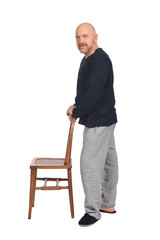 man in pajamas standing plaiyng with chair and looking at camera on white background