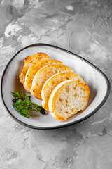 sliced bread in white plate on gray background
