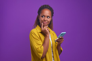 Young positive thoughtful African American woman smm specialist uses phone to manage company page...