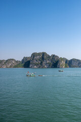 Fishing boats sailing across in Ha Long Bay