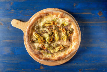 Top view of italian pizza with mozzarella, courgette flowers, anchovy fillets, green olives and...