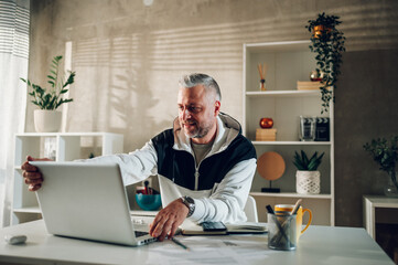 Middle aged man a laptop while working in a home office