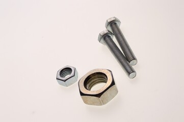 New, chrome-plated bolts and nuts of different sizes lie on a white background. Close-up