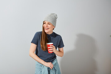 Happy excited woman looking away with coffee cup in teenage clothes.