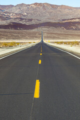street through the death valley desert with mountain ridge at horiron
