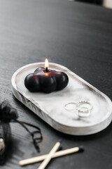 Handmade black figurative candle in a modern style, beautifully shaped.  Home decor, concrete stand on black table. 