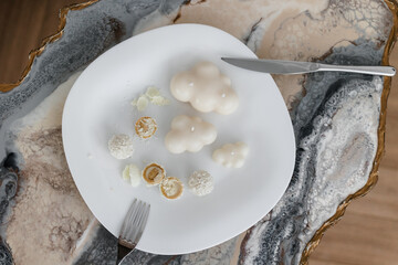 Shaped white candles handmade in a modern style, beautifully shaped on a white plate. serving plate with rafaelo candy. 