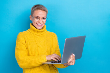 Photo of intelligent adorable lady wear stylish yellow winter sweater use netbook near empty space isolated on blue color background - obrazy, fototapety, plakaty