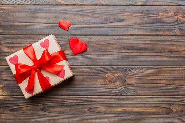 Top view photo of valentine day decorations gift box with red ribbon bow on colored background. Holiday gift boxes with top view