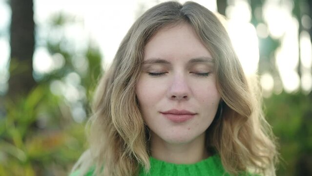 Young blonde woman breathing with closed eyes at park