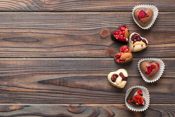 chocolate sweets in the form of a heart with fruits and nuts on a colored background. top view with space for text, holiday concept