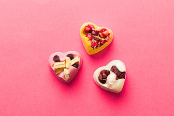 chocolate sweets in the form of a heart with fruits and nuts on a colored background. top view with space for text, holiday concept