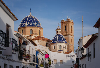 View of the church with blue domes from one of the main streets of the town of Altea on the Costa...