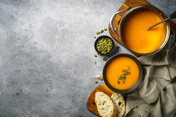 Pumpkin soup in the pot at stone table. Top view with copy space.