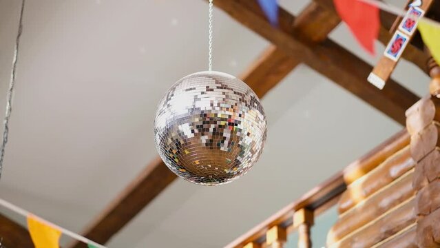 a silver disco ball is spinning on the ceiling of a bar, restaurant. The sun plays on the beautiful decor. High quality FullHD footage