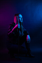 Cyber girl in a black leather jacket at dusk holds a katana. A woman in a club with a colored...