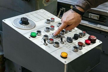 The worker controls the control panel for switching modes of grinding on a cylindrical grinding...